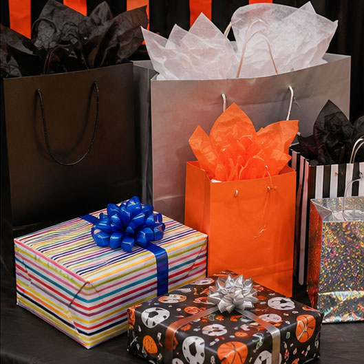 Wrapped birthday presents and gift bags displayed on a decorated party table with orange and black accents.